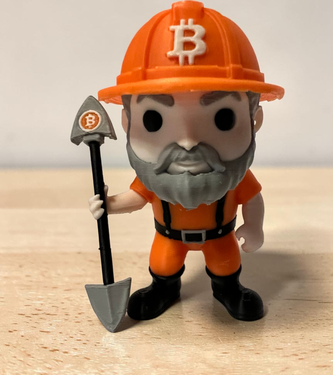 3D printed Bitcoin Miner Figure wearing an orange hard hat and holding a mining shovel