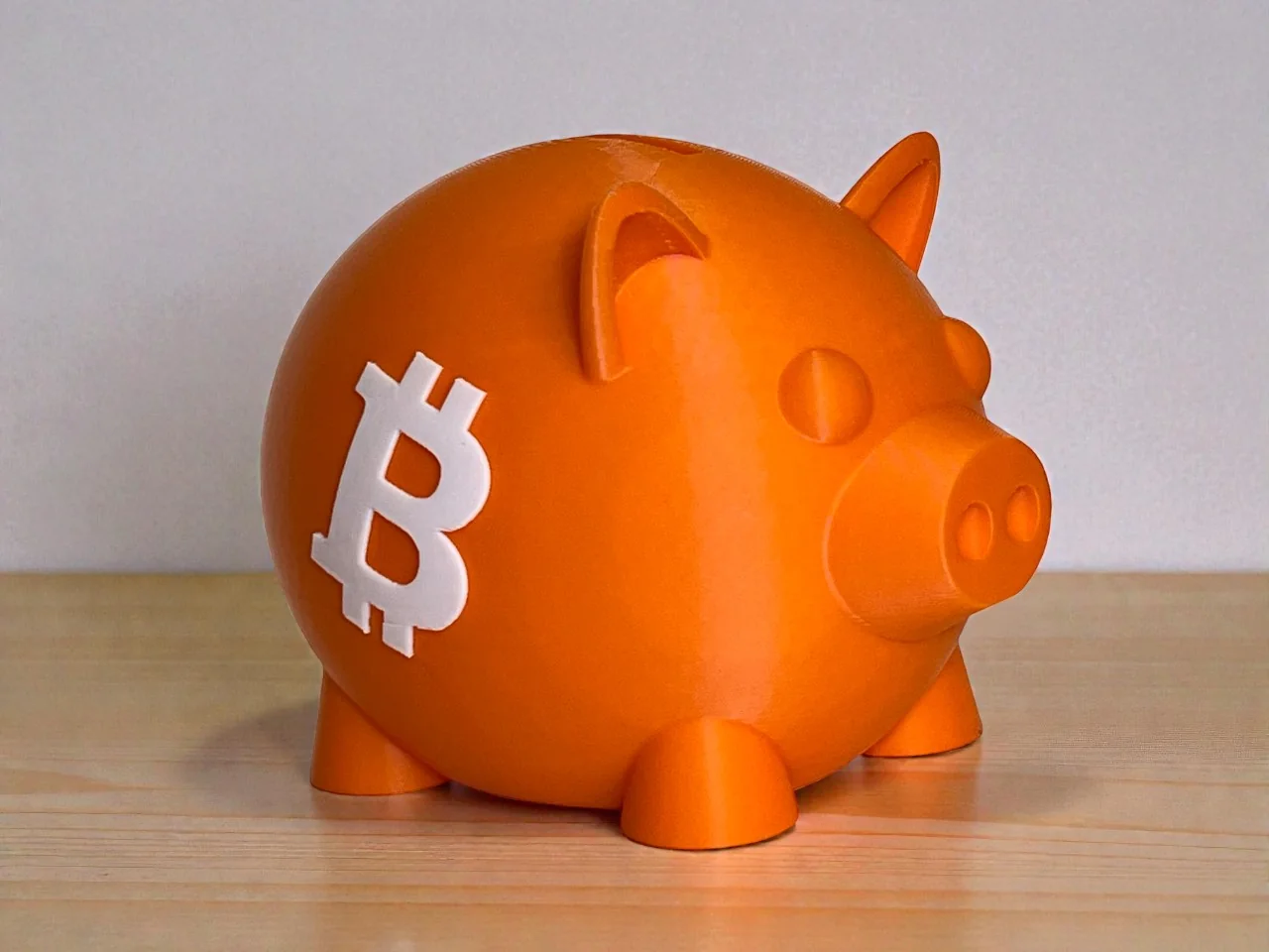 Orange 3D printed Bitcoin piggy bank with white Bitcoin emblem