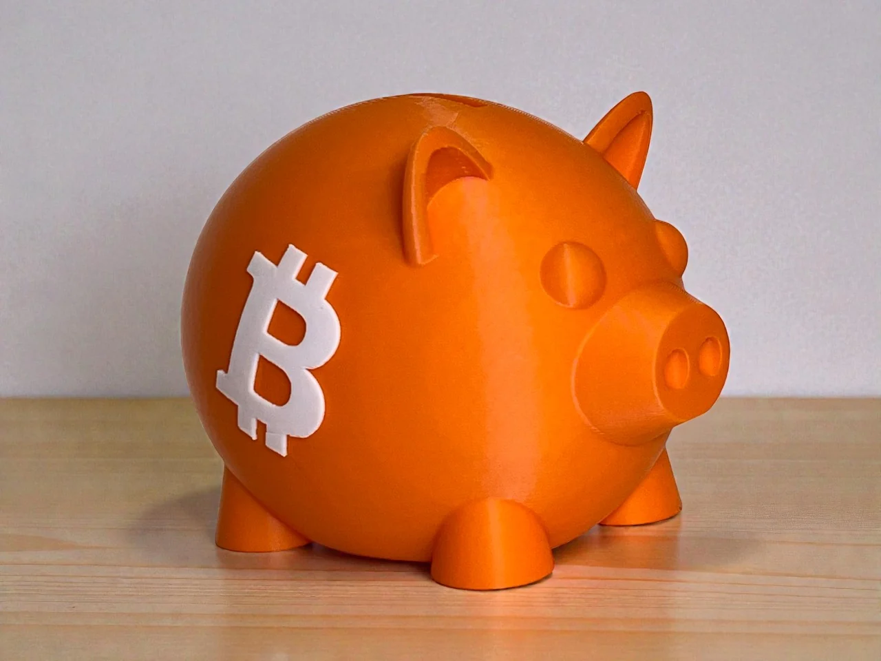 Orange 3D printed Bitcoin piggy bank with white Bitcoin logo